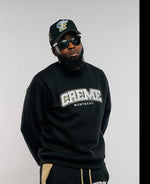 Load image into Gallery viewer, A person wearing a black sweatsuit featuring a CREME MONTREAL logo, paired with a matching cap and sunglasses. The clothing has gold accents, including side stripes and drawstrings, creating a stylish urban look.
