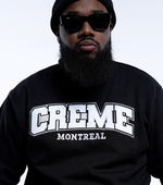 Load image into Gallery viewer, A person wearing a black sweatshirt featuring the bold CREME MONTREAL logo in white letters. The individual pairs the clothing with sunglasses and a beanie, exuding a casual, stylish vibe.
