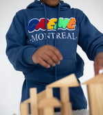 Load image into Gallery viewer, A child wearing a blue hoodie with colorful Creme Montreal embroidery is playing with wooden blocks. The clothing features a comfortable, relaxed fit, ideal for kids engaged in creative activities.
